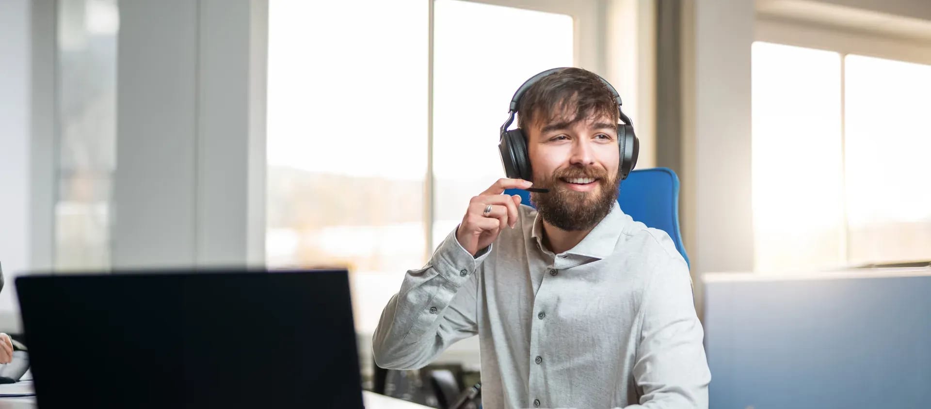 Mitarbeiter mit Headset am Schreibtisch im Kundengespräch
